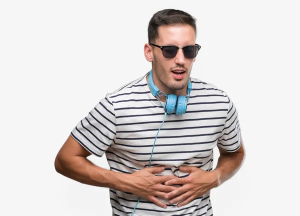 Joven Guapo Usando Auriculares Con Mano Estómago Porque Indigestión Enfermedad —  Fotos de Stock