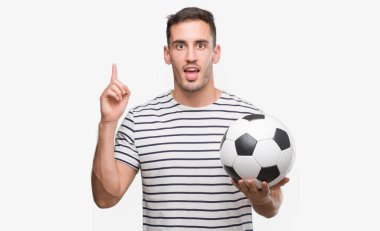 Futbol futbol sürpriz bir fikir ya da soru işaret parmağı ile gülen yüz, bir numara tutarak yakışıklı genç