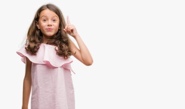 Brunette hispanic girl wearing pink dress pointing finger up with successful idea. Exited and happy. Number one. clipart