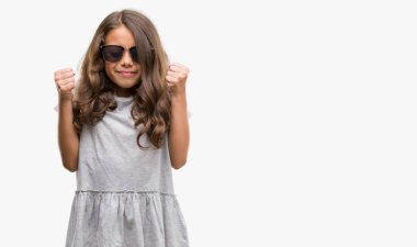 Esmer Latin kız silah ile başarı için heyecanlı güneş gözlüğü takıyor zafer kutluyor gülümseyen kaldırdı. Kazanan kavramı.