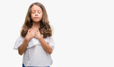 Esmer Latin kız göğüs kapalı gözlerle ellerinde ve yüzünde minnettar jest ile gülümseyen. Sağlık kavramı.