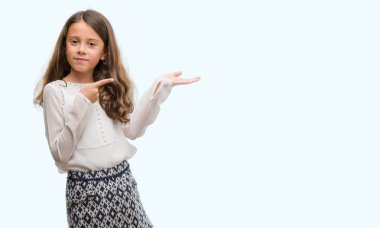 Hayret ve el ile sunulması ve parmak ile işaret ederken kameraya gülümseyen esmer Latin kız.