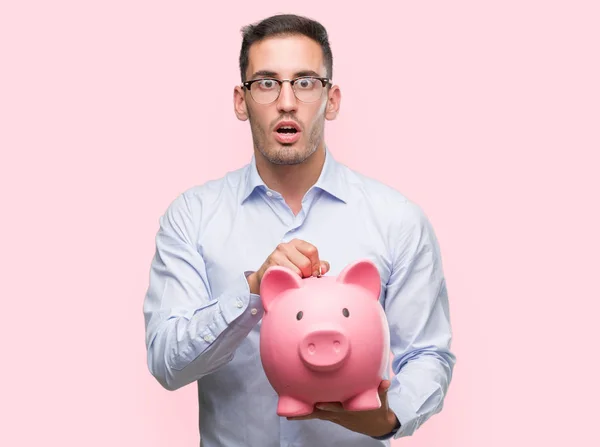 Bonito Jovem Segurando Banco Porquinho Assustado Choque Com Uma Cara — Fotografia de Stock