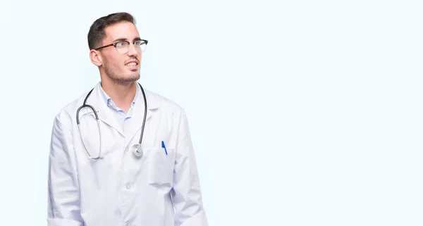 Joven Doctor Guapo Mirando Hacia Otro Lado Con Sonrisa Cara — Foto de Stock