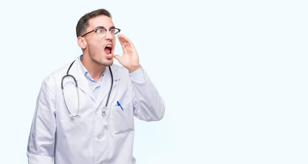 Guapo Joven Doctor Gritando Gritando Fuerte Lado Con Mano Boca — Foto de Stock