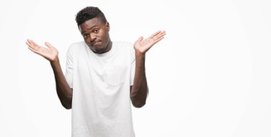 Beyaz t-shirt clueless ve şaşkın bir ifadeyle kollar ve eller kaldırdı giyen genç Afro-Amerikan adam. Şüphe kavramı.