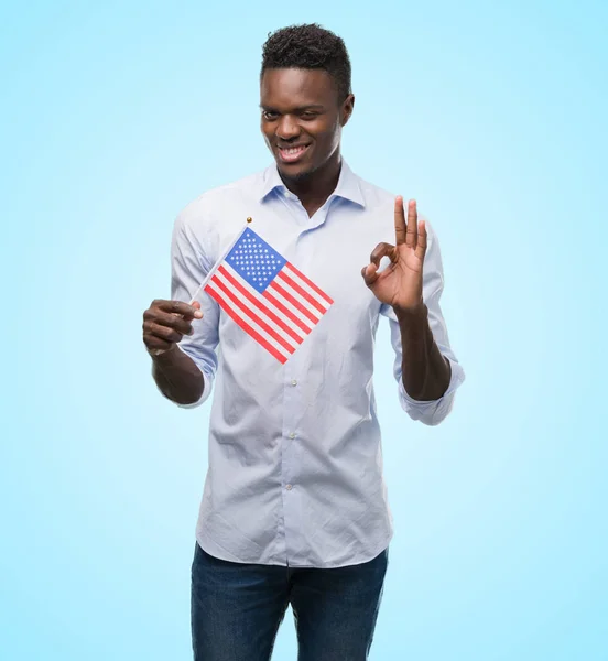 優秀なシンボルの指で サインをしているアメリカの国旗を保持している若いアフリカ系アメリカ人 — ストック写真