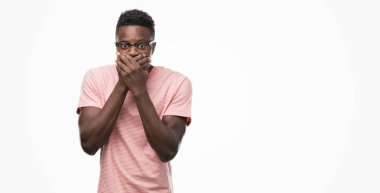 Pembe t-shirt ağız hata için elleriyle kapsayan şok giyen genç Afro-Amerikan adam. Gizli kavramı.