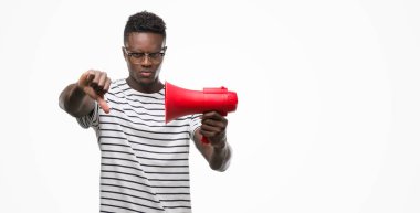 Başparmak aşağı, ret kavramı ile eksi işareti gösteren genç Afro-Amerikan adam holding megafon kızgın yüzü ile sevmemek