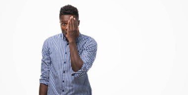 El yüz ve sürpriz duygu kendinden emin gülümseme ile tek gözüyle kapsayan mavi gömlek giymiş genç Afro-Amerikan adam.