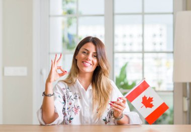 Genç kadın evde parmak, mükemmel sembolü ile ok işareti yapıyor Kanada bayrağı tutarak