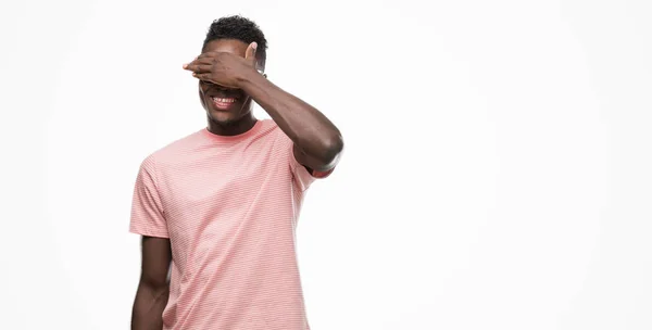若いアフリカ系アメリカ人の男は微笑し 笑う顔驚きの目を覆っている手でピンクの シャツを着てします 視覚障害者の概念 — ストック写真