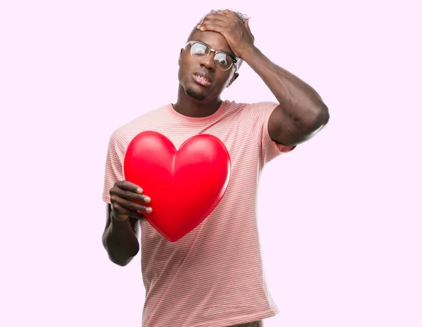 Unga Afroamerikanska Mannen Håller Rött Hjärta Stressad Med Handen Huvudet — Stockfoto