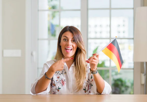 Ung Kvinna Hemma Hålla Flagga Tyskland Mycket Glad Pekar Med — Stockfoto