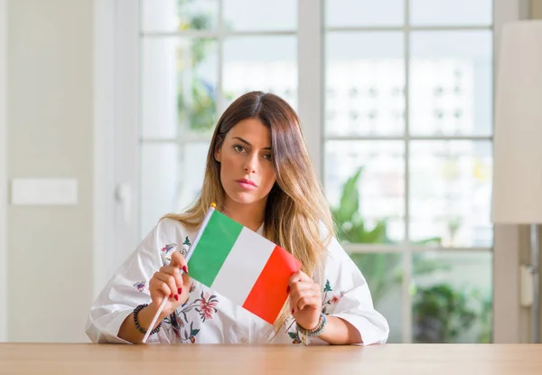 Молодая Женщина Дома Держит Флаг Италии Уверенным Выражением Умном Лице — стоковое фото