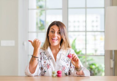 Genç kadının evde el ve parmak ile mutlu yüz gülümseyen ile yukarıyı macarons yediğini