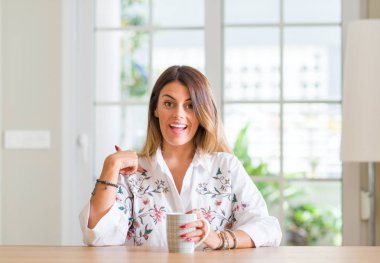 Genç kadın evde sürpriz yüz işaret parmağı kendine kahve içme