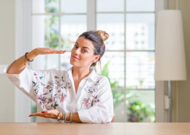 Genç kadın evde büyük ve büyük boy işaret, gösteren elleriyle işaret ölçmek sembolü. Kameraya bakarak gülümsüyordu. Ölçüm kavramı.