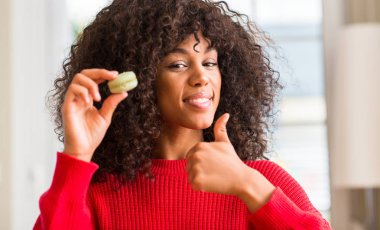 Macaron ok işareti, başparmak ile parmak, mükemmel işareti yapıyor kocaman bir gülümseme ile mutlu tutan Afrikalı-Amerikalı kadın