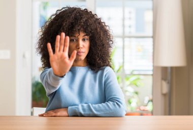 Afrikalı-Amerikalı kadın evde elin avuç ile şarkı stop yapıyor. Negatif ve ciddi bir jest yüz ifadesiyle uyarı.