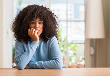 Afrikalı-Amerikalı kadın evde stresli ve gergin elle çivi ısırma ağzına bakıyor. Anksiyete sorunu.