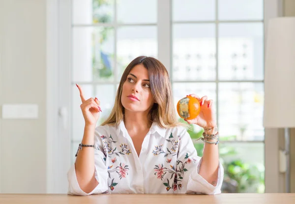 Mujer Joven Casa Sosteniendo Naranja Podrida Muy Feliz Señalando Con — Foto de Stock