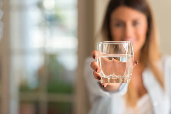 家庭での水のガラスを押しながら笑みを浮かべて美しい若い女性 ライフ スタイルのコンセプト — ストック写真