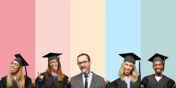 Senior teacher with his graduate students looking at camera showing tongue and making victory sign with fingers