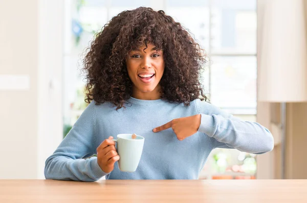 Африканская Американка Держащая Дома Чашку Кофе Неожиданным Лицом Указывающим Пальцем — стоковое фото