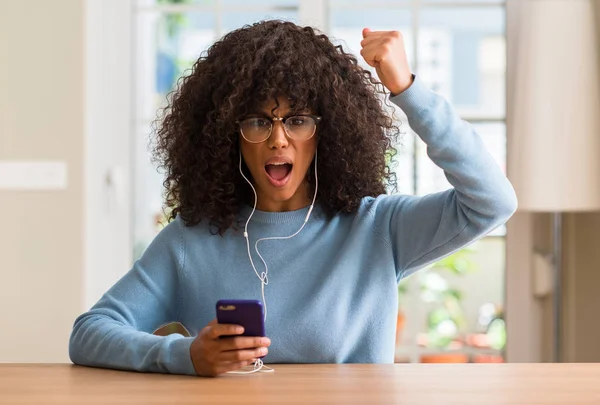 Akıllı telefon kullanan güzel Afrikalı-Amerikalı kadın rahatsız ve boşa çıkarmak ile öfke, çılgın da yükseltilmiş el ile bağırmaya kavramı öfke
