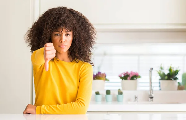 在厨房穿着黄色毛衣的非洲裔美国妇女看着不高兴和愤怒显示拒绝和否定与拇指向下手势 错误的表达式 — 图库照片