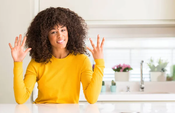 Африканская Американка Жёлтом Свитере Кухне Показывает Пальцем Номер Девять Улыбаясь — стоковое фото