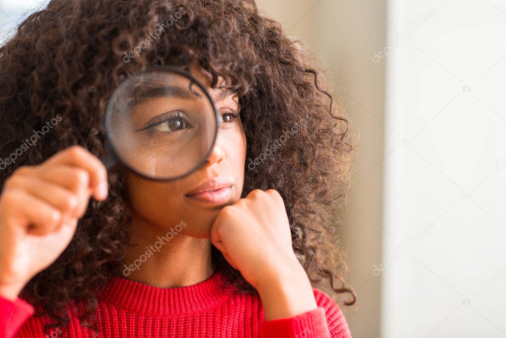 Curious african american woman looking through magnifying glass serious face thinking about question, very confused idea