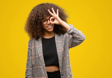 Mutlu yüz el parmaklarının arasından seyir göz üzerinde ok işaretiyle yapıyor gülümseyen bir ceket giyen Afrikalı-Amerikalı kadın