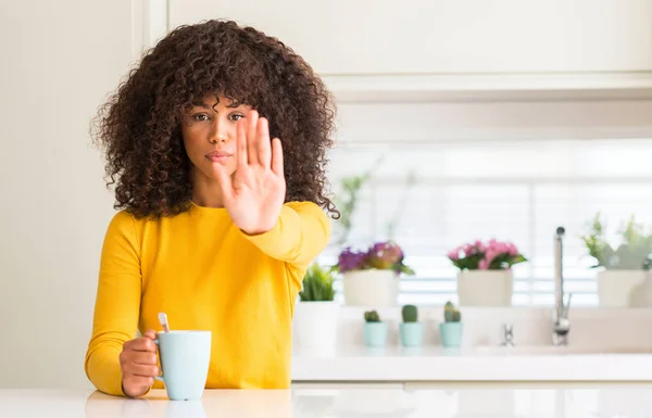 美丽的非洲裔美国妇女拿着一杯咖啡在家里与张开手做停止标志认真和自信的表达 防御姿态 — 图库照片