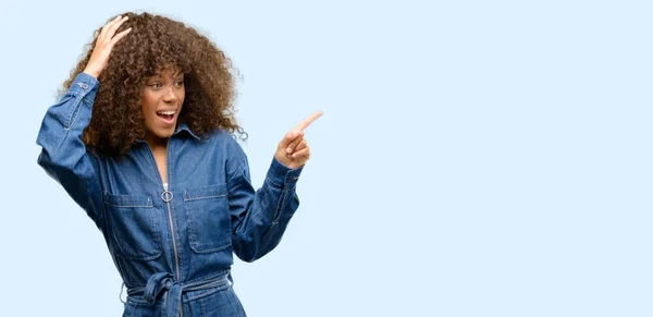 Afrikanerin Trägt Blauen Overall Und Zeigt Mit Finger Zur Seite — Stockfoto