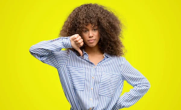 非洲裔美国妇女身穿条纹衬衫与愤怒的脸 消极的迹象显示不喜欢拇指向下 拒绝概念 — 图库照片