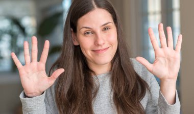 Genç güzel kadın evde gösterilen ve parmak sayısı on kendinden emin ve mutlu gülümseyerek süre ile yukarı dönük.