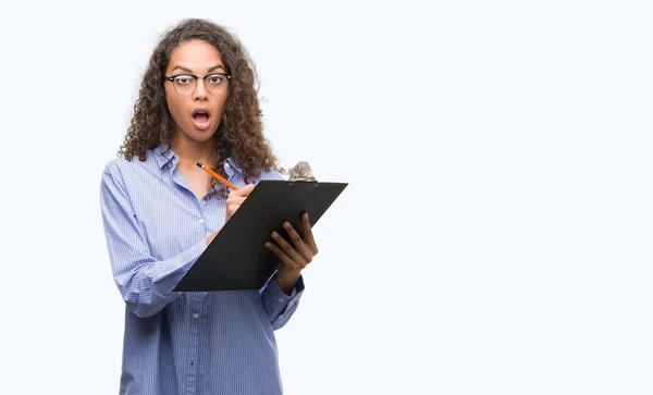 Young Hispanic Business Woman Holding Clipboard Scared Shock Surprise Face — Stock Photo, Image