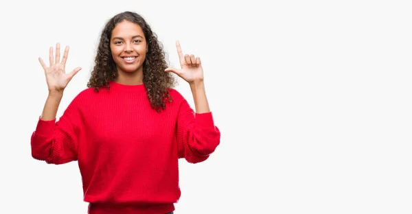 指で上向きの表示と赤いセーターを着ている若いヒスパニック女性数は自信を持って 幸せな笑みを浮かべている間 — ストック写真