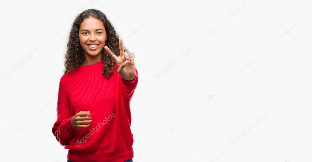 Young hispanic woman wearing red sweater smiling looking to the camera showing fingers doing victory sign. Number two.