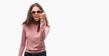 Güzel genç İspanyol kadın öfkeli ve sinirli sinirli ve öfke ile bağırarak süre öfkeli yumruk yükselterek güneş gözlüğü takıyor. Öfke ve agresif kavramı.