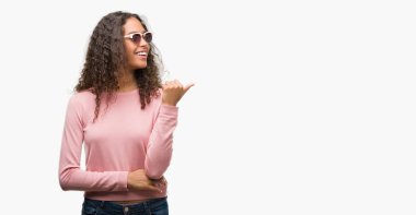 Güzel genç İspanyol kadın arıyorum ve başparmak yanında yukarıyı mutlu yüz ile gülümseyen güneş gözlüğü takıyor.