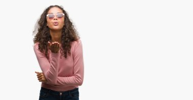 Güzel genç İspanyol kadın bir öpücük el ile güzel ve seksi olmak hava üfleme kamera bakarak güneş gözlüğü takıyor. Aşk ifade.