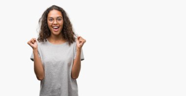 Güzel genç İspanyol kadın kutluyor gözlük takan şaşırttı ve başarı için kaldırdı kollarını açarak hayret ve gözleri açık. Kazanan kavramı.