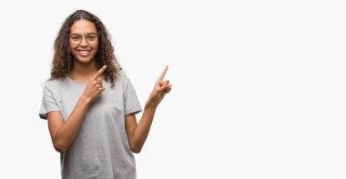 Güzel genç İspanyol kadın gülümseyerek ve iki elleri ve parmakları ile tarafına işaret kamera bakarak gözlüklü.