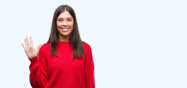 Gösterilen ve parmakları ile işaret kırmızı kazak giyen genç güzel İspanyol kendinden emin ve mutlu gülümseyerek süre beş numara.