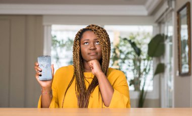Afrikalı-Amerikalı kadın kırık smartphone ciddi bir yüz düşünme hakkında soru, çok karışık fikir gösterilen