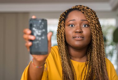 Afrikalı-Amerikalı kadın kırık smartphone korkmuş şok bir sürpriz yüz, korkuyor ve heyecanlı korku ifadesi ile gösterilen