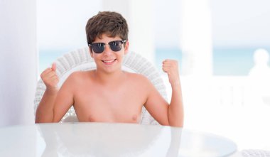 Duygu tezahürat genç çocuk gurur çığlık ve zafer ve başarı çok heyecanlı, kutluyor plajda bir sandalyede oturan tatil günleri